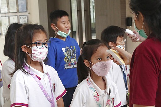 Staff members check students' body temperatures upon their arrival at Jakarta Nanyang School in Serpong on the outskirts of Jakarta, Indonesia, Tuesday, March 3, 2020. Indonesia confirmed its first cases of the coronavirus Monday in two people who contracted the illness from a foreign traveler. (AP Photo/Tatan Syuflana)