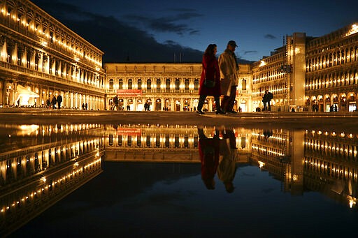 Local and tourists walk along a nearly empty St. Mark's square in Venice, Italy, Tuesday, March 3, 2020. G-7 countries say they are ready to take action to cushion the economic impacts of the new coronavirus outbreak, a statement that comes after a few days of wild market swings. (AP Photo/Francisco Seco)