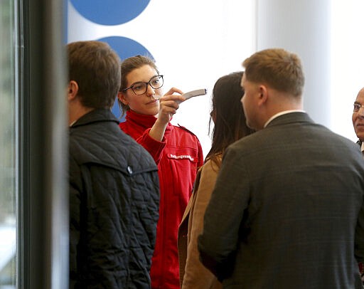 Austrian rescue personnel checks the body temperature of persons during an informal meeting of oil ministers of the Organization of Petroleum Exporting Countries, OPEC, at the OPEC headquarters in Vienna, Austria, Wednesday, March 4, 2020. (AP Photo/Roland Zak)