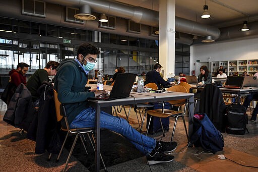 A student wearing a face mask sits in the library of the Politecnico University in Milan, Italy, Wednesday, March 4, 2020. Italy's virus outbreak has been concentrated in the northern region of Lombardy, but fears over how the virus is spreading inside and outside the country has prompted the government to close all schools nationwide for two weeks. (Claudio Furlan/LaPresse via AP)