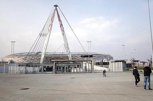 In this picture taken on March 1, 2020 a child rides his bicycle outsited a closed Allianz Stadium in Turin, northern Italy. The Italian Cup semifinal between Juventus and AC Milan scheduled for Wednesday, March 4, 2020 in Turin has been postponed indefinitely as part of measures to stop the spread of the virus outbreak in Italy. (Marco Alpozzi/LaPresse via AP)