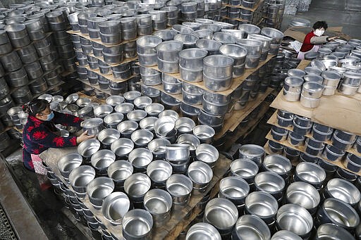 FILE - In this Feb. 27, 2020, file photo, workers arrange stew pots at a factory making kitchen utensils for export in Hangzhou in eastern China's Zhejiang province. Factories in China that make the world's smartphones, toys and other consumer goods are trying to protect their employees from a virus outbreak as they resume production. Manufacturers are buying masks by the thousands and jugs of disinfectant. The ruling Communist Party has told local officials to help reopen factories that were idled by the most intensive anti-disease controls ever imposed.   (Chinatopix via AP, File)