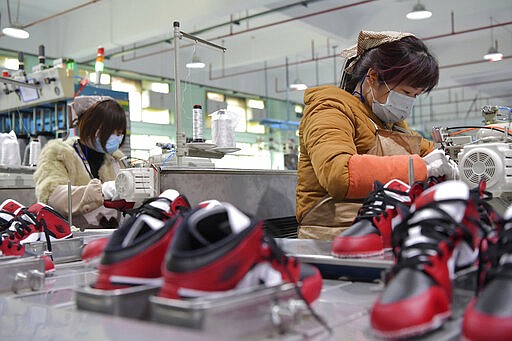 In this photo taken on Feb. 22, 2020 and released by Xinhua News Agency, workers wear mask as they manufacture shoes at a factory in the town of Xiangtang, Nanchang county in eastern China's Jiangxi Province. Factories in China that make the world's smartphones, toys and other consumer goods are trying to protect their employees from a virus outbreak as they resume production. Manufacturers are buying masks by the thousands and jugs of disinfectant. The ruling Communist Party has told local officials to help reopen factories that were idled by the most intensive anti-disease controls ever imposed. (Peng Zhaozhi/Xinhua via AP)