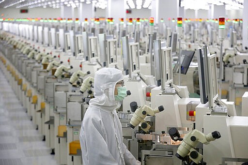 In this Feb. 20, 2020, photo, a worker sits at a production line at a microelectronics factory in Nantong in eastern China's Jiangsu Province. China on Friday suspended more punitive tariffs on imports of U.S. industrial goods in response to a truce in its trade war with Washington that threatened global economic growth. (Chinatopix via AP)