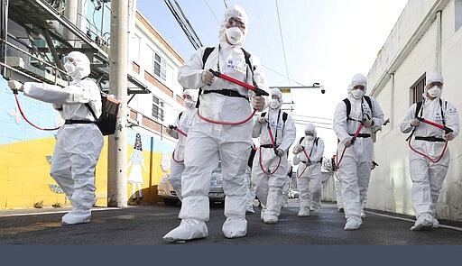 South Korean army soldiers wearing protective gears spray disinfectant as a precaution against the new coronavirus on a street in Gyeongan, South Korea, Wednesday, March 4, 2020. (Kim Hyun-tae/Yonhap via AP)