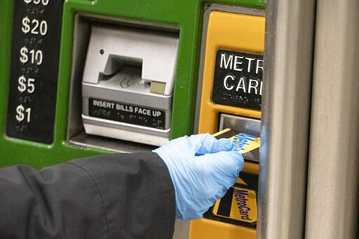 A woman wears a protective glove as she purchases a metro card at a subway station, Wednesday, March 4, 2020, in New York. She said that she always wears gloves in the subway &quot;because it's filthy.&quot; According to the Centers for Disease Control and Prevention, (CDC), &quot;It may be possible that a person can get COVID-19 by touching a surface or object that has the virus on it and then touching their own mouth, nose, or possibly their eyes, but this is not thought to be the main way the virus spreads.&quot; (AP Photo/Mark Lennihan)