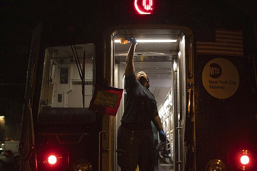 A Metropolitan Transportation Authority worker sanitizes surfaces at the Coney Island Yard, Tuesday, March 3, 2020, in the Brooklyn borough of New York. The MTA is stepping up efforts to sanitize cars and stations as fears mount over the coronavirus. (AP Photo/Kevin Hagen)