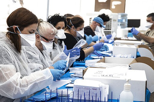 Electoral officials count ballots cast by Israelis under home quarantine after returning from Coronavirus infected zones in the city of Shoham, Israel, Wednesday, March 4, 2020. (AP Photo/Tsafrir Abayov)