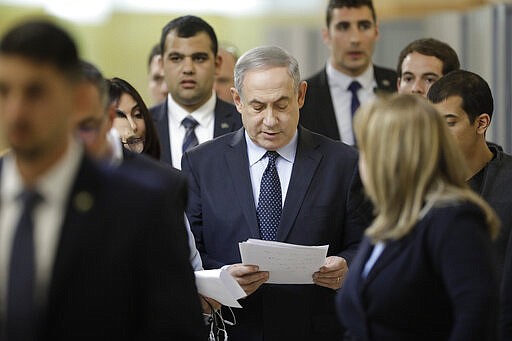 Israeli Prime Minister Benjamin Netanyahu reads from his notes as he walks to a meeting with his nationalist allies and his Likud party members at the Knesset, the Israeli Parliament, in Jerusalem, Wednesday, March 4, 2020. Israel looks set to slide back into political deadlock as the final votes were being tallied from the country's third election in less than a year. (AP Photo/Sebastian Scheiner)