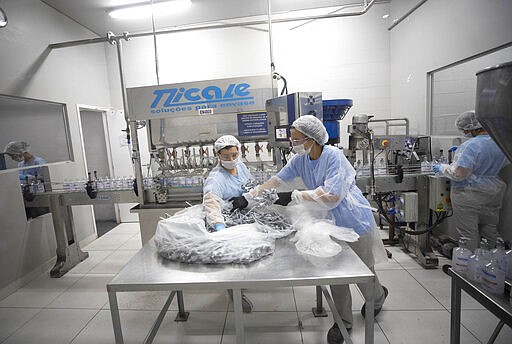 Worker produce hand sanitizer at the Companhia Nacional do &Aacute;lcool (CNA) factory in Piracicaba, Brazil, Tuesday, March 3, 2020. Last week the factory added a second shift of workers to produce more hand sanitizer, and while the CNA was never an exporter, it's considering that by adding a third shift. One week ago, Brazil confirmed Latin America&#146;s first case of the new coronavirus. (AP Photo/Andre Penner)