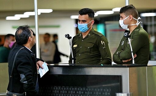 Police officers wear masks at Baghdad Airport, Iraq, Wednesday, March 4, 2020. From religion to sports, countries were taking drastic and increasingly visible measures to curb the new coronavirus that first emerged in China and was spreading quickly through Europe, the Mideast and the Americas. (AP Photo/Hadi Mizban)