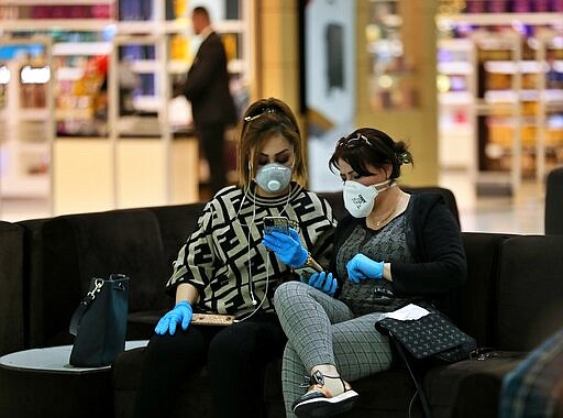 Passengers wear protective masks while waiting for their plane in Baghdad Airport, Iraq, Wednesday, March 4, 2020.  From religion to sports, countries were taking drastic and increasingly visible measures to curb the new coronavirus that first emerged in China and was spreading quickly through Europe, the Mideast and the Americas. (AP Photo/Hadi Mizban)