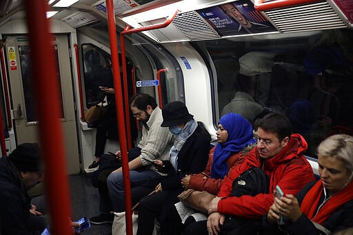 A woman wearing a face mask sits on an underground train on the Central Line in London, Wednesday, March 4, 2020. British authorities laid out plans Tuesday to confront a COVID-19 epidemic, saying that the new coronavirus could spread within weeks from a few dozen confirmed cases to millions of infections, with thousands of people in the U.K. at risk of death. (AP Photo/Matt Dunham)