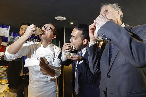 Italian Foreign Minister Luigi Di Maio, center, eats a pizza with French Ambassador to Rome Christian Masset, right, and pizza maker Gino Sorbillo, in Sorbillo's restaurant, in Rome, Wednesday, March 4, 2020. According to reports, Di Maio invited the French ambassador for a pizza after French channel Canal plus broadcast a satirical video of a fake Italian pizza maker coughing on a pizza and calling it &quot;Corona Pizza&quot;. (AP Photo/Andrew Medichini)