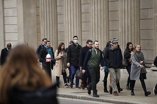 A man wearing a face mask walks past the Bank of England in London, Wednesday, March 4, 2020. British authorities laid out plans Tuesday to confront a COVID-19 epidemic, saying that the new coronavirus could spread within weeks from a few dozen confirmed cases to millions of infections, with thousands of people in the U.K. at risk of death. (AP Photo/Matt Dunham)