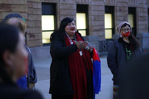 Candi Brings Plenty, center, prays outside the Capitol in Pierre, S.D., Tuesday evening, March 3, 2020, before a Senate committee heard testimony on a bill to revamp the state's riot laws. (AP Photo/Stephen Groves)