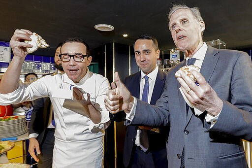 Italian Foreign Minister Luigi Di Maio, center, eats a pizza with French Ambassador to Rome Christian Masset, right, and pizza maker Gino Sorbillo, in Sorbillo's restaurant, in Rome, Wednesday, March 4, 2020. According to reports, Di Maio invited the French ambassador for a pizza after French channel Canal plus broadcast a satirical video of a fake Italian pizza maker coughing on a pizza and calling it &quot;Corona Pizza&quot;. (AP Photo/Andrew Medichini)