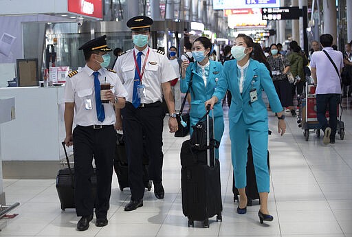 Flight crew wear protective masks as they arrive at the Suvarnabhumi Airport in Bangkok, Thailand, Wednesday, March 4, 2020. (AP Photo/Sakchai Lalit)