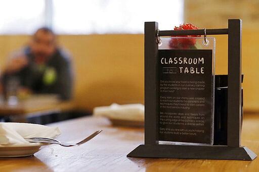 This Jan. 29, 2020, photo shows a sign on a table at Inspiration Kitchens in Chicago. From Hawaii to Pennsylvania, states are scrambling to blunt the impact, with roughly 700,000 people at risk of losing benefits unless they meet certain work, training or school requirements. Inspiration Corporation, a nonprofit, runs the training kitchen and restaurant out of a converted Chicago warehouse. (AP Photo/Nam Y. Huh)