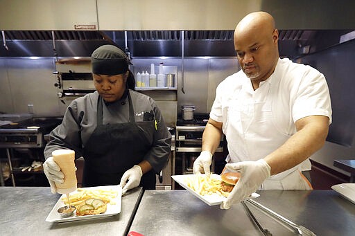 In this Jan. 29, 2020, photo, chef Samara Henderson, left, works with trainee Anthony Redmond at Inspiration Kitchens in Chicago. Redmond, 44, started receiving food stamps when he was released from prison last summer. With the help, he was able to leave a halfway house and find his own place. After the training, he hopes to find employment and keep his benefits. (AP Photo/Nam Y. Huh)