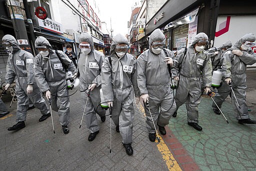 Army soldiers wearing protective suits spray disinfectant as a precaution against the new coronavirus at a shopping street in Seoul, South Korea, Wednesday, March 4, 2020. The coronavirus epidemic shifted increasingly westward toward the Middle East, Europe and the United States on Tuesday, with governments taking emergency steps to ease shortages of masks and other supplies for front-line doctors and nurses. (AP Photo/Ahn Young-joon)