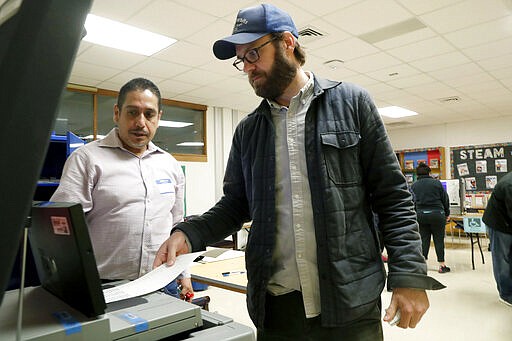 Dallas County election worker Maxx Nu&ntilde;ez helps Democrat Jamie Wilson cast his ballot in the Super Tuesday primary at John H. Reagan Elementary School in the Oak Cliff section of Dallas, Tuesday, March 3, 2020. (AP Photo/LM Otero)