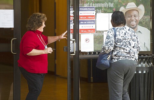 An election worker holds the door open for a resident at the C.L. Simon Recreation Center in Nacogdoches, Texas, during voting hours on Tuesday, March 3, 2020.  (Tim Monzingo/The Daily Sentinel via AP)