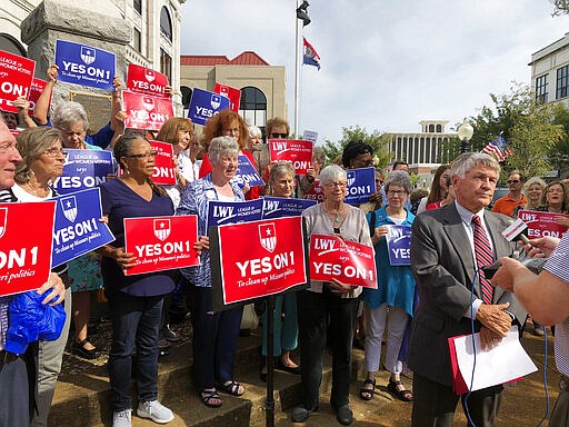 FILE - In this Aug. 31, 2018 file photo, supporters of Missouri's redistricting ballot measure hold signs behind former state Sen. Bob Johnson as he serves as their spokesman during a press conference outside the Cole County Courthouse in Jefferson City, Mo. With the U.S. census approaching, some state lawmakers are attempting to alter voter-approved measures that were intended to reduce partisan gamesmanship when drawing new districts for the U.S. House and state legislatures. (AP Photo/David A. Lieb, File)