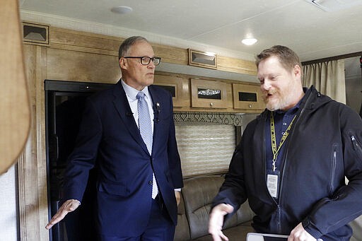 Washington Gov. Jay Inslee, left, stands inside a recreation vehicle at a potential coronavirus isolation and quarantine site with Nathan Weed, incident commander for the coronavirus response team at Department of Health, Wednesday, March 4, 2020, in Centralia, Wash. Eight RVs are located at the site. (AP Photo/Rachel La Corte)