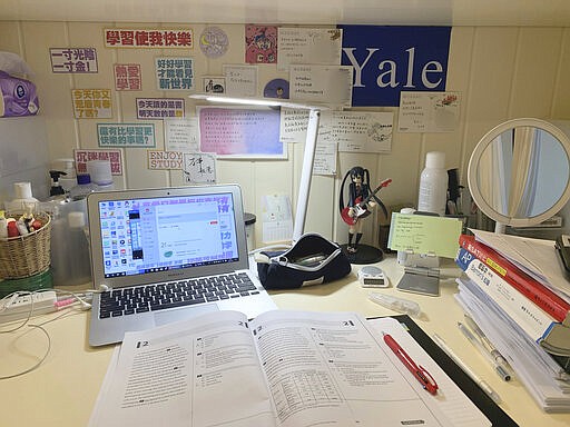 This Feb. 26, 2020 photo released by Tan Weiwei, shows a view of the 17-year-old's desk in Changsha, in southern China's Hunan province. She spent her winter break studying for the SAT, an exam that foreign students must take to enroll in American universities, facing a wall plastered with motivational slogans. When the March exam she was registered for in Malaysia was canceled due to concerns over the coronavirus, she said she felt lost and anxious about what it could mean for her dream of studying in the U.S.  (Tan Weiwei via AP)