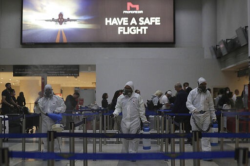 Workers wearing protective gear spray disinfectant as a precaution against the coronavirus outbreak, in the departure terminal at the Rafik Hariri International Airport, in Beirut, Lebanon, Thursday, March 5, 2020. The novel coronavirus has infected more than 80,000 people globally, causing around 2,700 deaths, mainly in China. (AP Photo/Hassan Ammar)