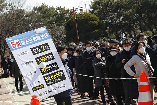 An employee holds a board to give face mask sales informations as people line up to buy face masks to protect themselves from the new coronavirus outside Nonghyup Hanaro Mart in Seoul, South Korea, Thursday, March 5, 2020. The number of infections of the COVID-19 disease spread around the globe. The signs read &quot;Face mask sales informations on March 5, Sale time: PM 2:00 and Sales quantity: 1,500 people.&quot;(AP Photo/Ahn Young-joon)