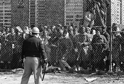 FILE - In this Feb. 4, 1965, file photo, a policeman stands guard outside a fence surrounding the Perry County Jail in Marion, Ala., as arrested civil rights demonstrators chant and sing freedom songs. As the 55th anniversary of the civil rights clash known as Bloody Sunday approaches, townspeople in Alabama want to remind the world that the road to Selma began in a place called Marion. (AP Photo/Horace Cort, File)