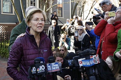 Sen. Elizabeth Warren, D-Mass., with her husband Bruce Mann's hand on her shoulder, speaks to the media outside her home, Thursday, March 5, 2020, in Cambridge, Mass., after she dropped out of the Democratic presidential race. (AP Photo/Steven Senne)