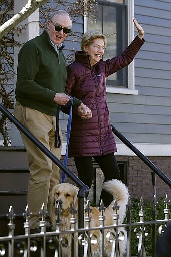 Sen. Elizabeth Warren, D-Mass., with her husband Bruce Mann, and dog Bailey in front, leave her home, Thursday, March 5, 2020, in Cambridge, Mass., to speak to the media after she dropped out of the Democratic presidential race. (AP Photo/Steven Senne)