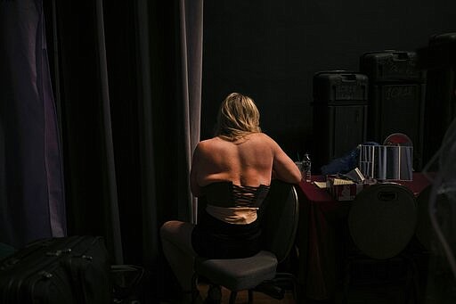 Deborah Smith sits in the dressing area as she sorts through her outfits for a fashion show on Friday, Jan. 31, 2020, in Boston ahead of the TransFORMED show which features male-to-female crossdressers. But over time, the focus has become less about the clothes, and more about the people in them. (AP Photo/Wong Maye-E)