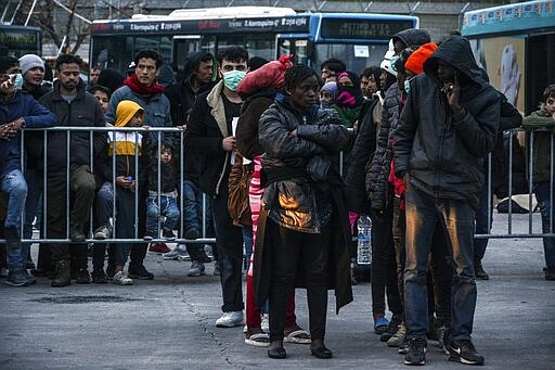 Migrants stand as others wait to enter buses at the port of Mytilene on the northeastern Aegean island of Lesbos, Greece, on Wednesday, March 4, 2020. Turkey made good on a threat to open its borders and send migrants into Europe last week. In the past few days hundreds of people have headed to Greek islands from the nearby Turkish coast in dinghies. (AP Photo/Panagiotis Balaskas)