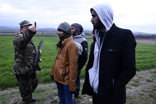 A Greek army officer detains migrants in the village of Ardanio at the Greek-Turkish border on Wednesday, March 4, 2020. Greek authorities fired tear gas and stun grenades Wednesday morning to repulse a push by migrants to cross its land border from Turkey, as pressure continued along its frontier after Turkey said its own border with Europe was open to whoever wanted to cross. (AP Photo/Giannis Papanikos)