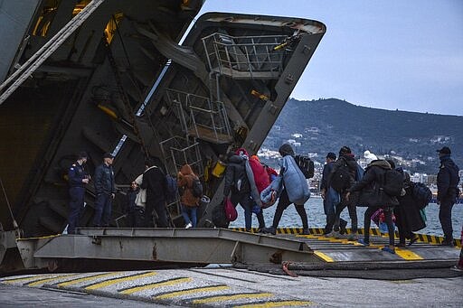 Migrants enter a Greek Navy ship which will accommodate them at the port of Mytilene on the northeastern Aegean island of Lesbos, Greece, on Wednesday, March 4, 2020. Turkey made good on a threat to open its borders and send migrants into Europe last week. In the past few days hundreds of people have headed to Greek islands from the nearby Turkish coast in dinghies. (AP Photo/Panagiotis Balaskas)