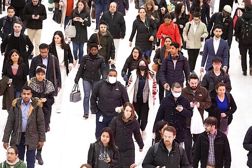 Three commuters, center, wear masks as they walk through the World Trade Center transportation hub, Wednesday, March 4, 2020, in New York. (AP Photo/Mark Lennihan)