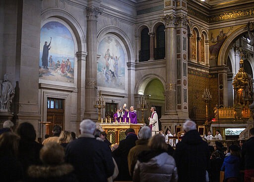 FILE - In this Sunday, March 1, 2020, file photo, a priest prepares to give the Holy Communion to faithful during a Mass celebrated at Saint Francois Xavier church in Paris, France. The archbishop of Paris is asking all of the French capital's parish priests to change the way they administer communion to counter the spread of the coronavirus. The Paris diocese said in a statement that a Paris priest tested positive for the virus after returning from Italy. (AP Photo/Rafael Yaghobzadeh, File)