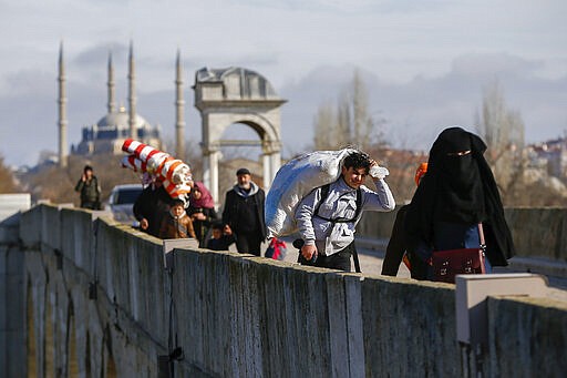 Migrants walk across a bridge in Edirne near the Turkish-Greek border on Thursday, March 5, 2020. Greece countered accusations from Turkey Wednesday that it was responsible for the death of a migrant, as its border authorities strove for a sixth day to keep thousands of migrants out by using tear gas, stun grenades and water cannons. (AP Photo/Emrah Gurel)