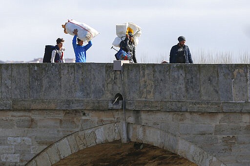 Migrants walk on a bridge in Edirne near the Turkish-Greek border on Thursday, March 5, 2020. Turkey has vowed to seek justice for a migrant it says was killed on the border with Greece after Greek authorities fired tear gas and stun grenades to push back dozens of people attempting to cross over. Greece had denied that anyone was killed in the clashes. (AP Photo/Darko Bandic)