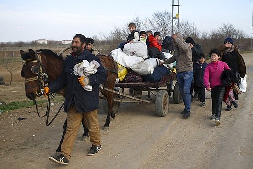 Migrants use a cart as others walk near the Turkish-Greek border in Pazarkule on Wednesday, March 4, 2020. Greek authorities fired tear gas and stun grenades Wednesday morning to repulse a push by migrants to cross its land border from Turkey, as pressure continued along its frontier after Turkey said its own border with Europe was open to whoever wanted to cross. (AP Photo/Emrah Gurel)