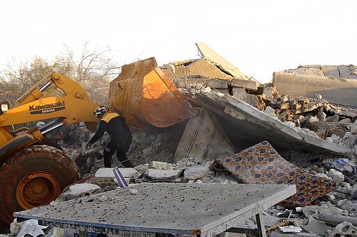 In this photo provided by the Syrian Civil Defense White Helmets, which has been authenticated based on its contents and other AP reporting, Syrian White Helmet civil defense workers supported by a bulldozer search for victims from under the rubble of a destroyed house that was hit by Syrian government and Russian airstrikes, in Maaret Musreen village, in Idlib province, Syria, Thursday, March 5, 2020. An airstrike on a rebel-held village in northwestern Syria early Thursday.. (Syrian Civil Defense White Helmets via AP)