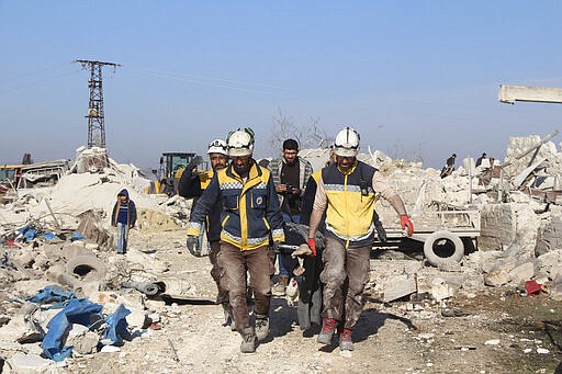 In this photo provided by the Syrian Civil Defense White Helmets, which has been authenticated based on its contents and other AP reporting, Syrian White Helmet civil defense workers carry a victim next of destroyed houses hit by Russian airstrikes, in Maaret Musreen village, in Idlib province, Syria, Thursday, March 5, 2020. An airstrike on a rebel-held village in northwestern Syria early Thursday. (Syrian Civil Defense White Helmets via AP)