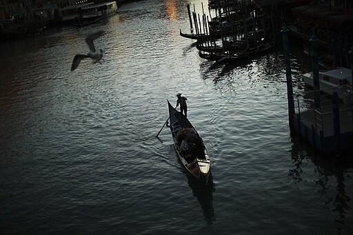 A gondolier on the Grand Canal as the sun sets in Venice, Italy, Friday, Feb. 28, 2020. Venice in the time of coronavirus is a shell of itself, with empty piazzas, shuttered basilicas and gondoliers idling their days away. Venice, a UNESCO world heritage site, had already been brought to its knees last year, when near-record high tides flooded a lagoon city used to frequent spells of &quot;aqua alta.&quot;(AP Photo/Francisco Seco)