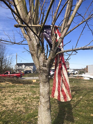 A tattered flag is lodged in a tree on Wednesday, March 4, 2020, after a tornado tore through a Putnam County, Tennessee, neighborhood Tuesday, destroying most of the homes.  (AP Photo/Travis Loller)