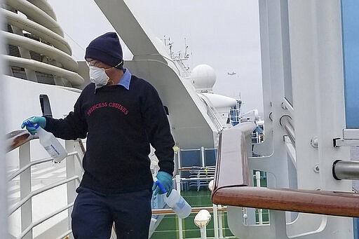 CORRECTS COAST GUARD TO NATIONAL GUARD-In this photo provided by Michele Smith, a cruise ship worker cleans a railing on the Grand Princess Thursday, March 5, 2020, off the California coast. Scrambling to keep the coronavirus at bay, officials ordered a cruise ship with about 3,500 people aboard to stay back from the California coast Thursday until passengers and crew can be tested, after a traveler from its previous voyage died of the disease and at least two others became infected. A National Guard helicopter lowered test kits onto the 951-foot (290-meter) Grand Princess by rope as the vessel lay at anchor off Northern California, and authorities said the results would be available on Friday. Princess Cruise Lines said fewer than 100 people aboard had been identified for testing. (Michele Smith via AP)