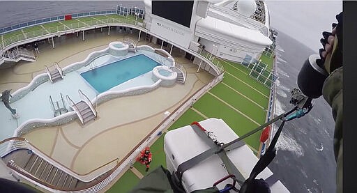 In this image from video, provided by the California National Guard, airmen with the 129th Rescue Wing drop virus testing kits down to the Grand Princess cruise ship off the coast of California Thursday, March 5, 2020. Scrambling to keep the coronavirus at bay, officials ordered a cruise ship with 3,500 people aboard to stay back from the California coast Thursday until passengers and crew can be tested, after a traveler from its previous voyage died of the disease and at least two others became infected. The California National Guard 129th Rescue Wing lowered test kits onto the 951-foot (290-meter) Grand Princess by rope as the vessel lay at anchor off Northern California, and authorities said the results would be available on Friday. Princess Cruise Lines said fewer than 100 people aboard had been identified for testing. (California National Guard via AP)